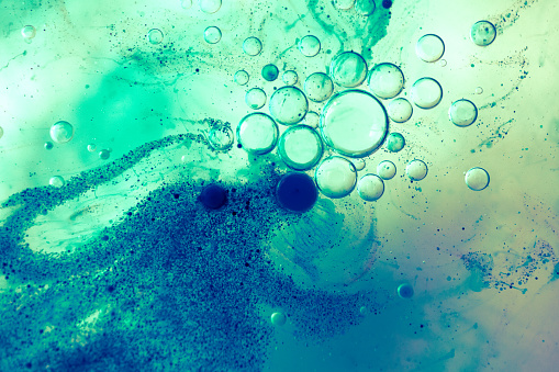 Oil, water and blue pigment particles abstract background with selective focus