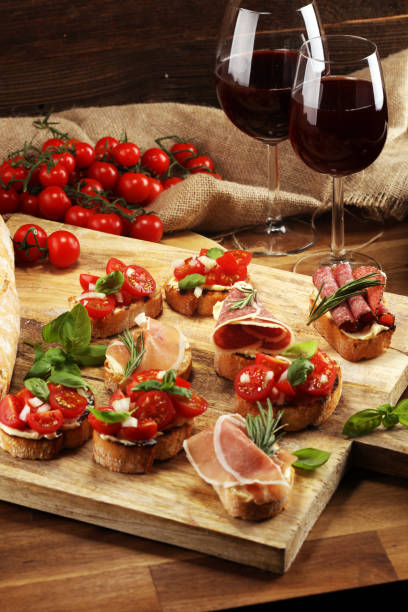 istock antipasto various appetizer. Cutting board with prosciutto, salami, cheese, bread and olives on dark wooden background 1153909784