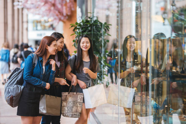 Young happy girls with shopping bags walking on street Image of three young attractive girls with shopping bags in the Taipei city. window shopping at night stock pictures, royalty-free photos & images