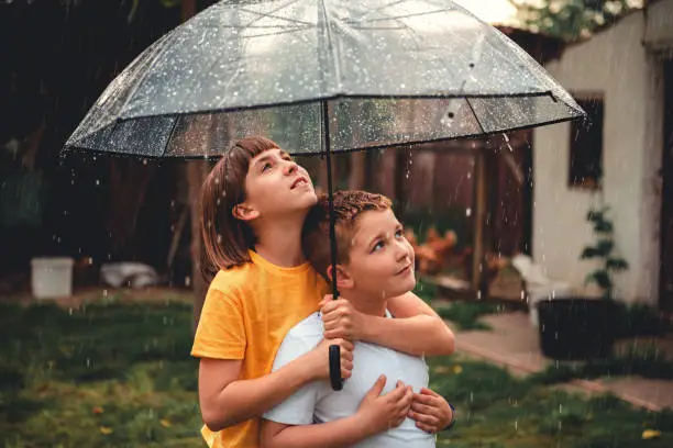 Photo of Brother and sister enjoying rain