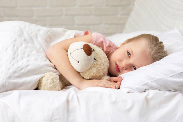 istock Cute little child girl sleeping with teddy bear 1153919257