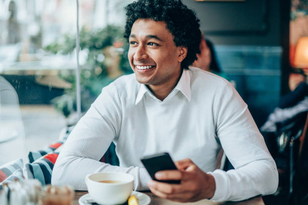 istock Afro-american man enjoying cup of tea and using smart phone 1153920100