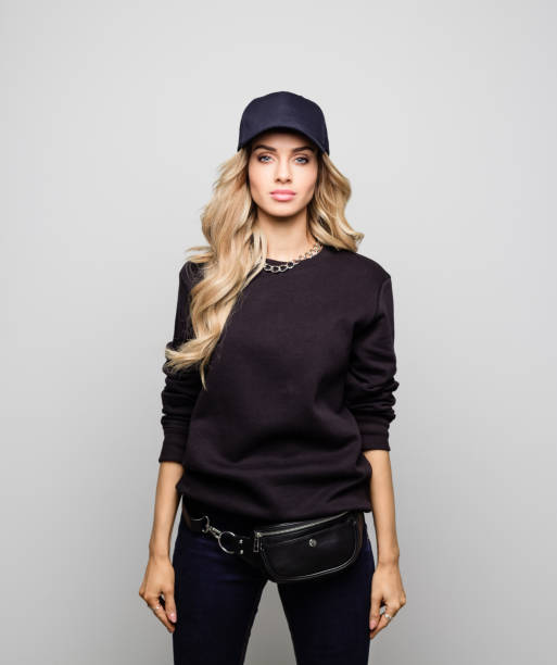 Portrait of beautiful young woman in street outfit Portrait of beautiful woman in street outfit. Confident young female is with long blond hair. Hipster is standing against white background. woman wearing baseball cap stock pictures, royalty-free photos & images