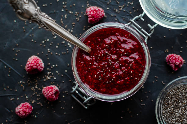 Homemade chia seeds jam Homemade raspberry jam with chia seeds in a jar with a spoon inside on black background. Healthy idea for breakfast toasts. Superfoods and healthy food concept. Top view. chia seed stock pictures, royalty-free photos & images