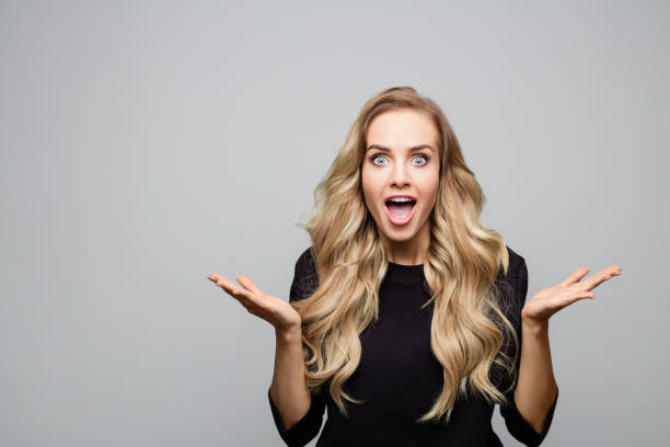 istock Surprised blond woman with hands raised 1153922445