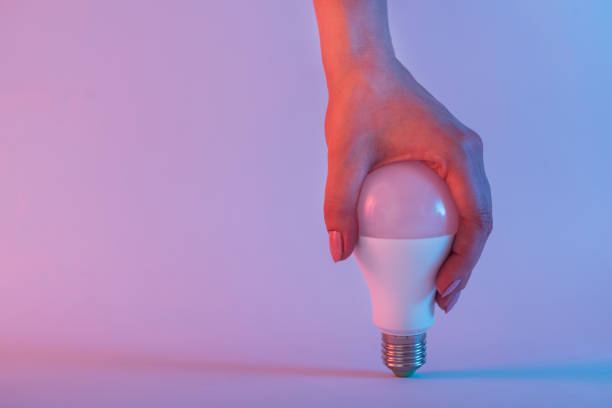 istock Light bulb in female hand. Neon colored background 1153925926