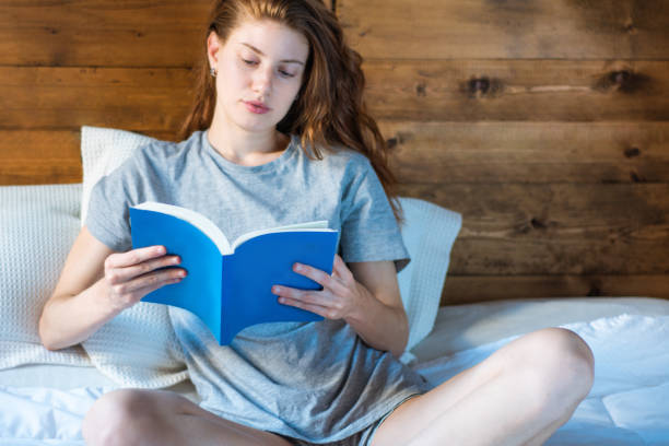 istock woman laying in bed and reading book 1153927500