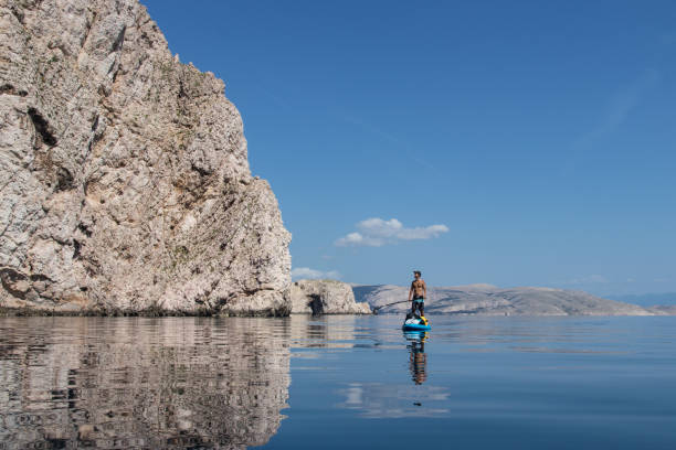 istock Man stand up paddling under the cliffs 1153929783