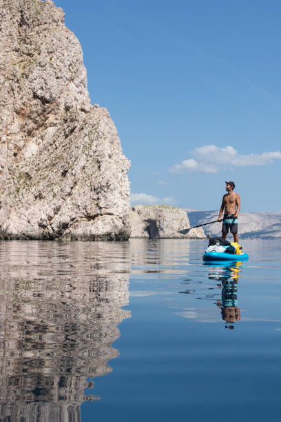 istock Man stand up paddling under the cliffs 1153929789