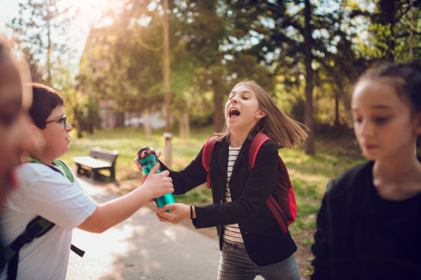 Boy fighting with girl over water bottle at schoolyard Boy fighting with classmate over water bottle at schoolyard schoolyard fight stock pictures, royalty-free photos & images