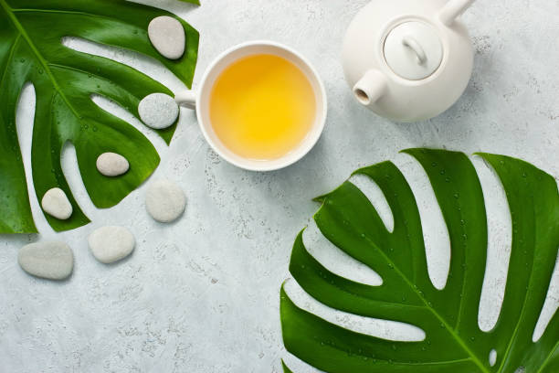 istock Oriental style  teapot on light   background with green monstera 1153934667