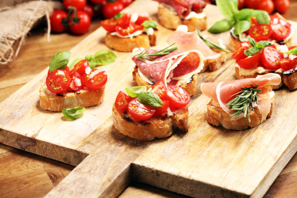 istock antipasto various appetizer. Cutting board with prosciutto, salami, cheese, bread and olives on dark wooden background 1153934681