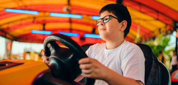 istock Boy driving bumper car in amusement park 1153936367