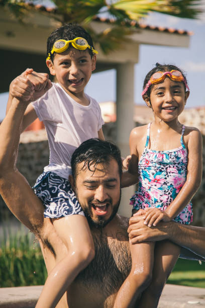 istock Mexican dad playing with kids in the pool 1153944469