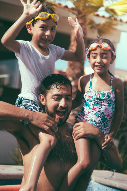 istock Mexican dad playing with kids in the pool 1153948052
