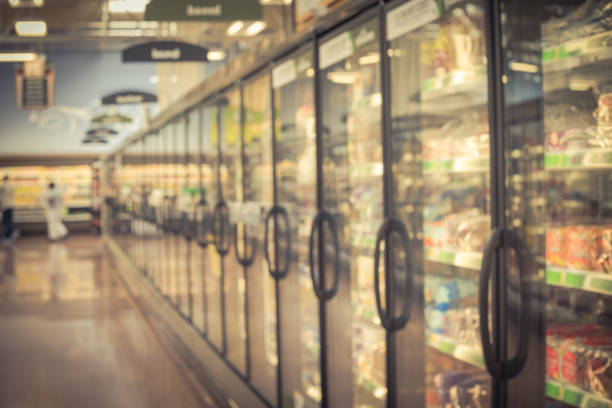 Blurry background customer shopping for frozen and processed foods at supermarket in USA Motion blurred customer shopping for frozen food section at retail store in US. Huge glass door aisle with variety pack of processed fruit, vegetable, breakfast, appetizer, side, meals, pizza refrigerated section supermarket photos stock pictures, royalty-free photos & images