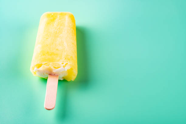 istock side view yellow popsicle on a light green background 1153954247