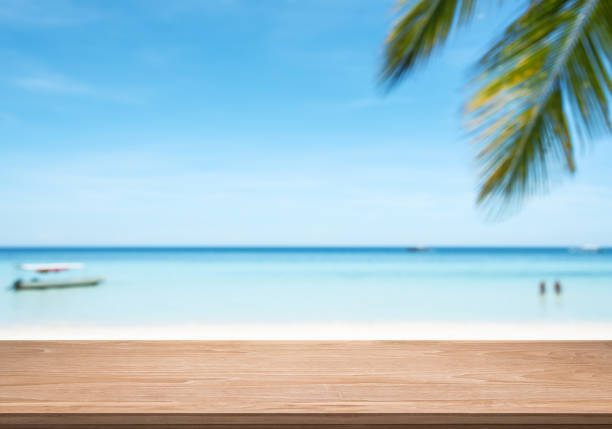 istock Empty wooden table with blurred tropical beach background 1153954595