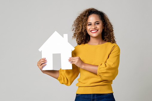 Portrait of young happy smiling African American woman holding paper home for real estate concept