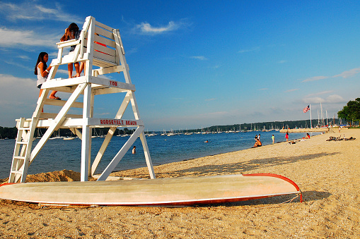 Oyster Bay, NY, USA June 30, 2009 Two young women chat on an empty lifeguard stand on the seashore in Oyster Bay, New York
