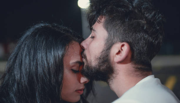 Young man kissing his girlfriend on her forehead