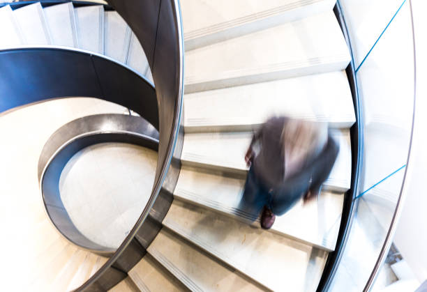 istock Blurred Motion of Man on Abstract Spiral Staircase 1153971585