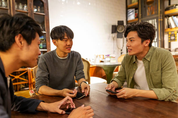 istock Happy Asian Men Talking in a Coffee Shop 1153973766