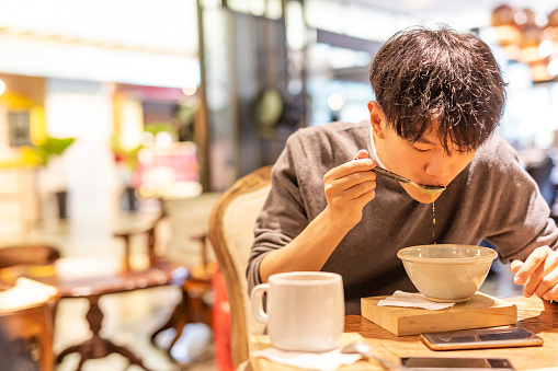 Young Asian Man Eating Soup in a Restaurant