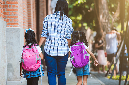 Back to school. Asian mother and daughter pupil girl with backpack holding hand and going to school together