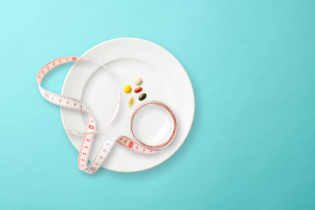 istock White plate with Tape Measure and Nutritional supplement on light blue background 1153979465