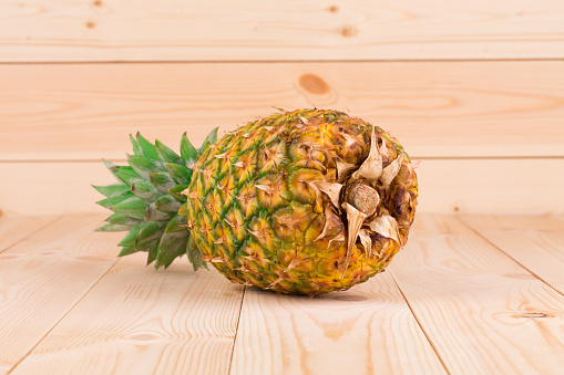 Fresh ripe pineapple. Located on a wooden surface. Close-up.