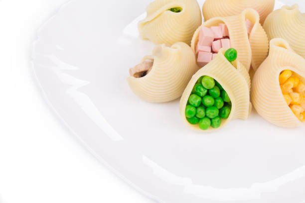 Pasta conchiglie stuffed with vegetables and sausage. It is located in a white backround. Close-up.