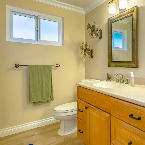 istock Square Double vanity with wooden cabinets inside a bathroom with small window 1153989901