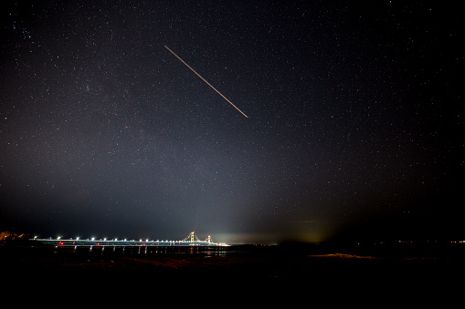 A night time view of a shooting star over the Mackinac Bridge from Mackinac City, MI March 2019