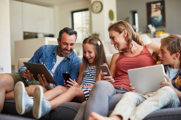 family fun for the smart generation Shot of a happy young family using wireless devices on the sofa at home equipment stock pictures, royalty-free photos & images
