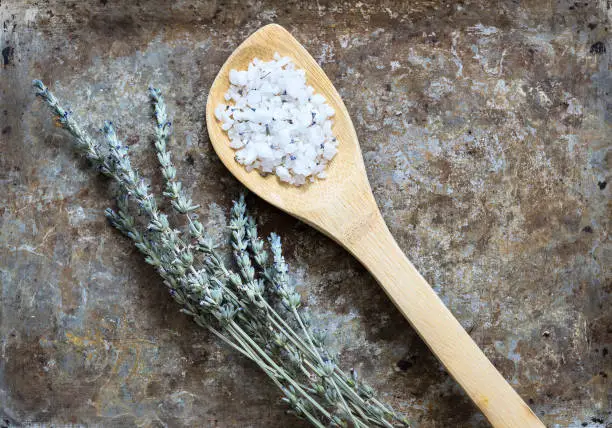 Dried lavender flatlay on rustic background with bathsalt in a spoon angled position