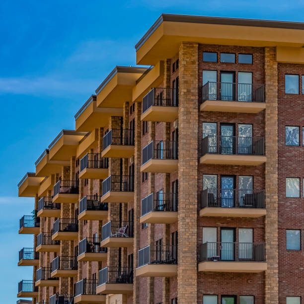 istock Square Residential brick building with balconies against blue sky with thin clouds 1153999019