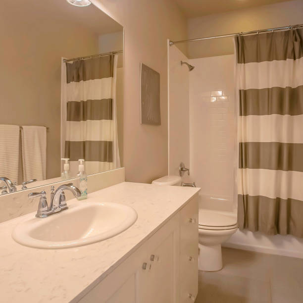 istock Frame Square Bathtub and shower with a striped curtain inside a small bathroom 1153999989