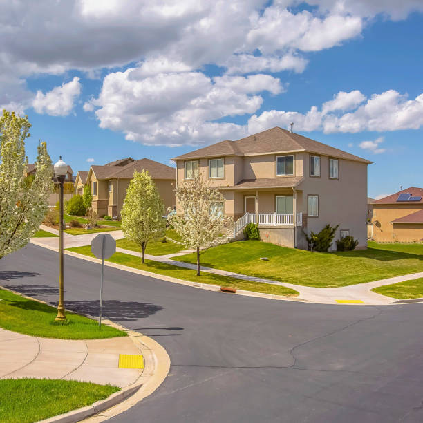 istock Square Paved road along lovely homes under blue sky with puffy clouds on a sunny day 1154000002