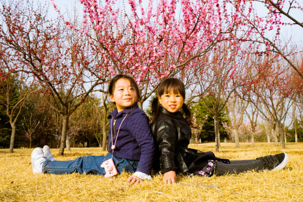 istock two young girls sitting on the grass 1154007348