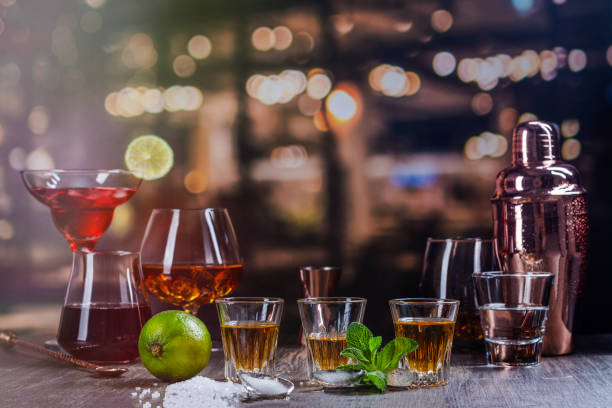 Strong alcohol drinks in bar Golden mexican tequila shots with lime and salt. Assortment of different strong alcohol drinks on bar counter over night lights background. Copy space bachelor and bachelorette parties stock pictures, royalty-free photos & images