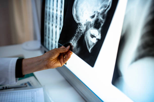Female Japanese doctor seated in her office and examining x-ray imagery before deciding on a diagnosis.