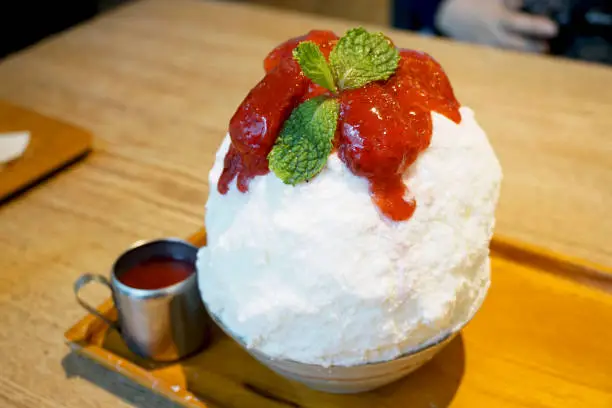Photo of Strawberry kakigori (Bingsu) - Japanese shaved ice dessert flavor, stuffed with cheesecake, topped with strawberry jam, Traditional summer dessert in Japan.