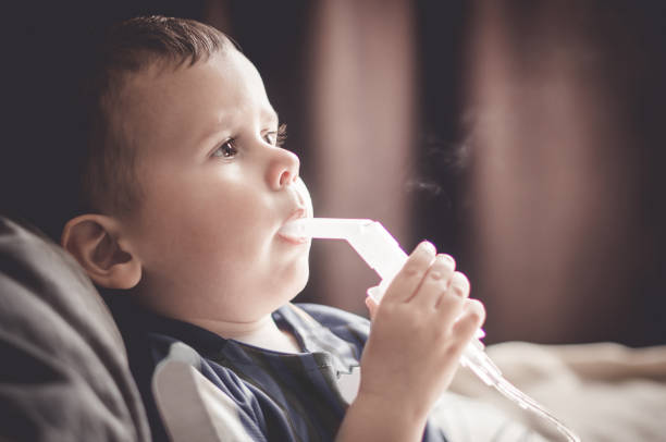 istock Two year old boy making inhalation with nebulizer at home. 1154020045