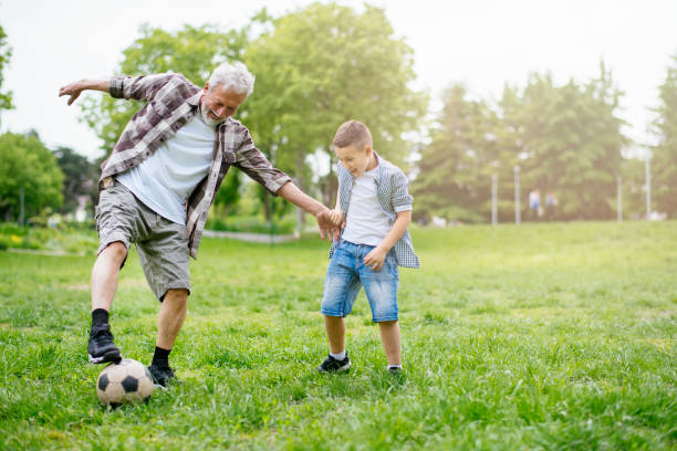 おじいちゃんと孫は楽しんで、サッカー - helmet child padding football helmet ストックフォトと画像