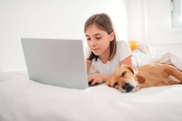 istock Girl lying on the bed with dog and using laptop 1154026693