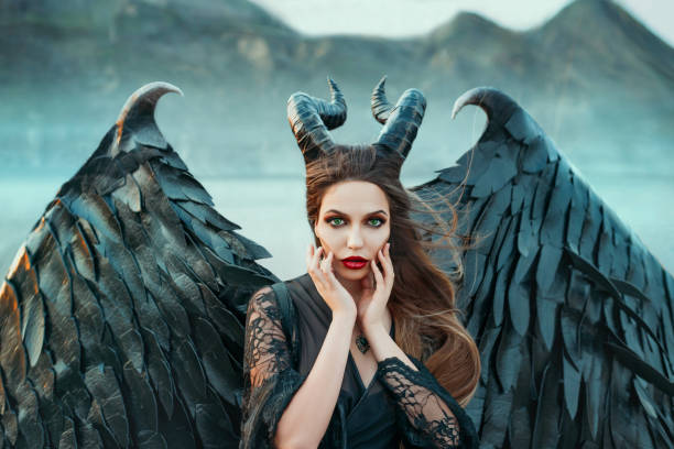 charming portrait of dark angel with sharp horns and claws on strong powerful wings, wicked witch in black lace dress brought hands to face, bright red lipstick and green eyes, art photo in blue shade - halloween horror vampire witch imagens e fotografias de stock
