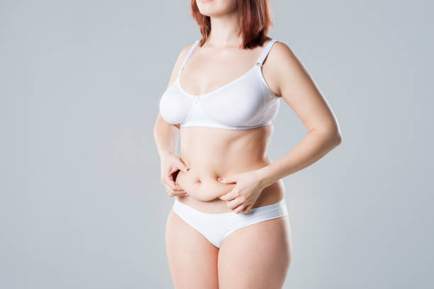 woman with fat flabby belly, overweight female body on gray background - overweight tummy tuck abdomen body imagens e fotografias de stock