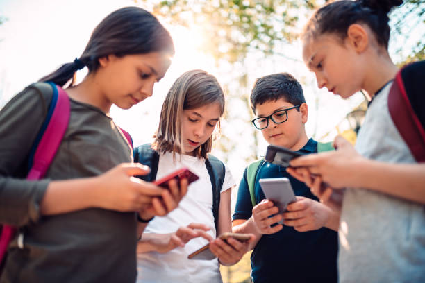 los niños jugando videojuegos en el teléfono inteligente después de la escuela - videojuego fotos fotografías e imágenes de stock