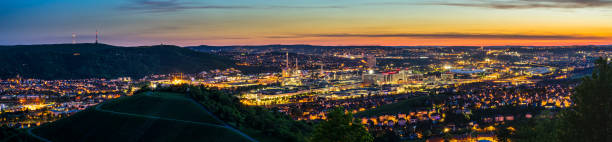 Germany, XXL panorama of magic illuminated skyline of downtown stuttgart city houses and arena after sunset from above stock photo